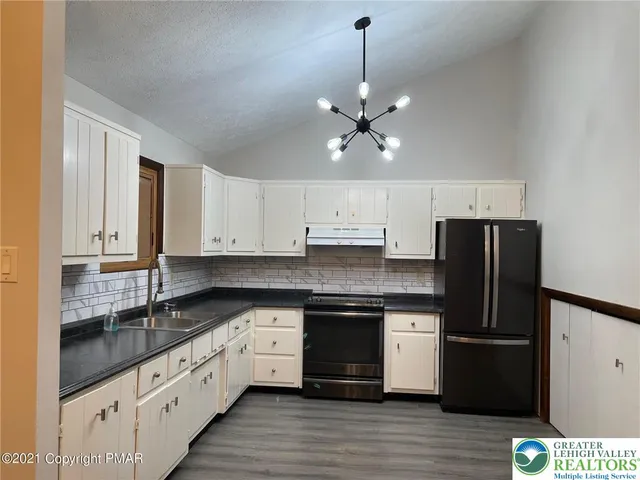 a kitchen with stainless steel appliances granite countertop a refrigerator a sink and white cabinets