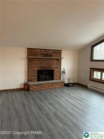 a view of empty room with wooden floor and fireplace
