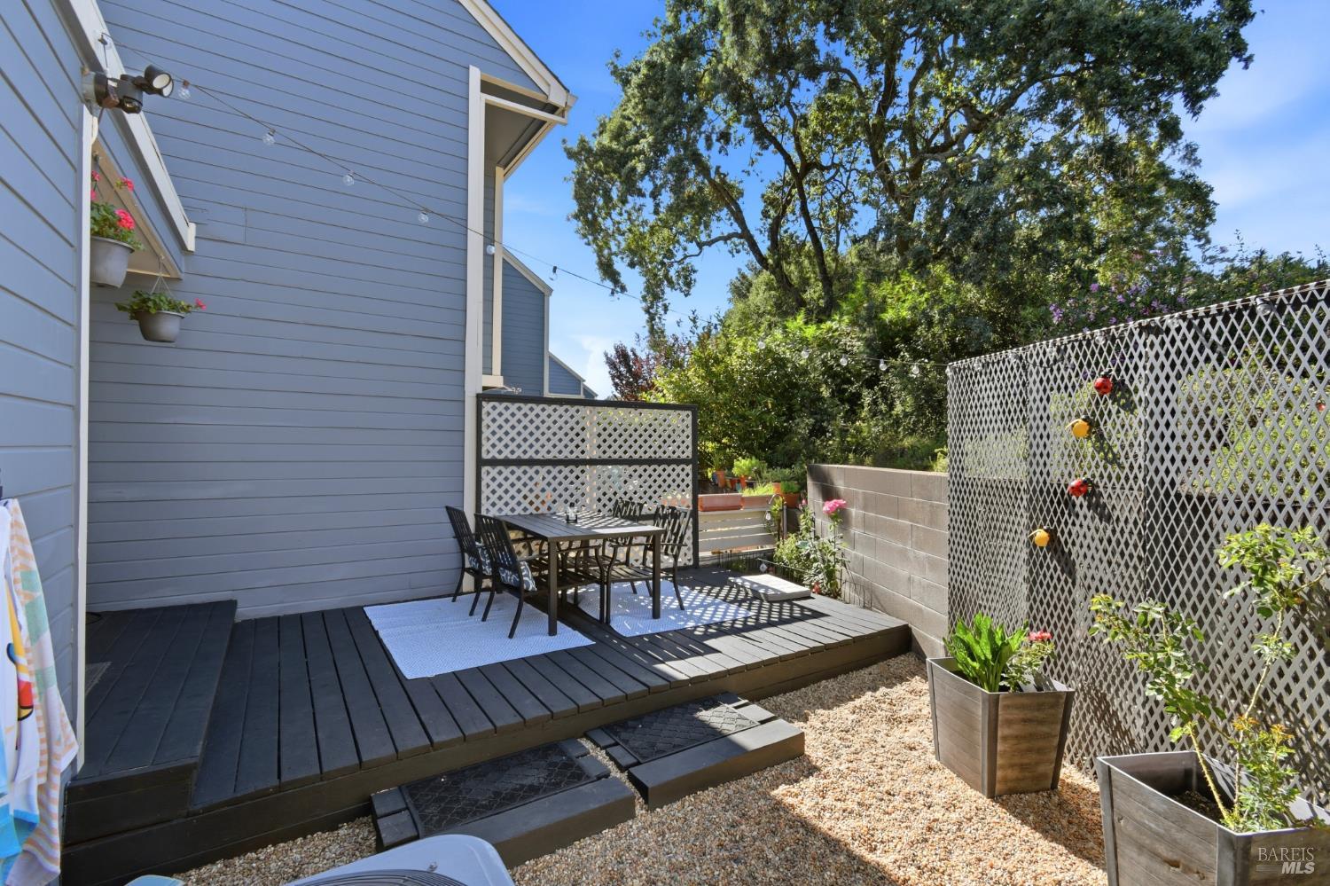 5193 Firestone Place Santa Rosa, CA 95409 - Photo 35 of 35 Low-maintenance backyard with a wood deck, gravel patio, raised planters, and lush greenery — a private outdoor retreat.