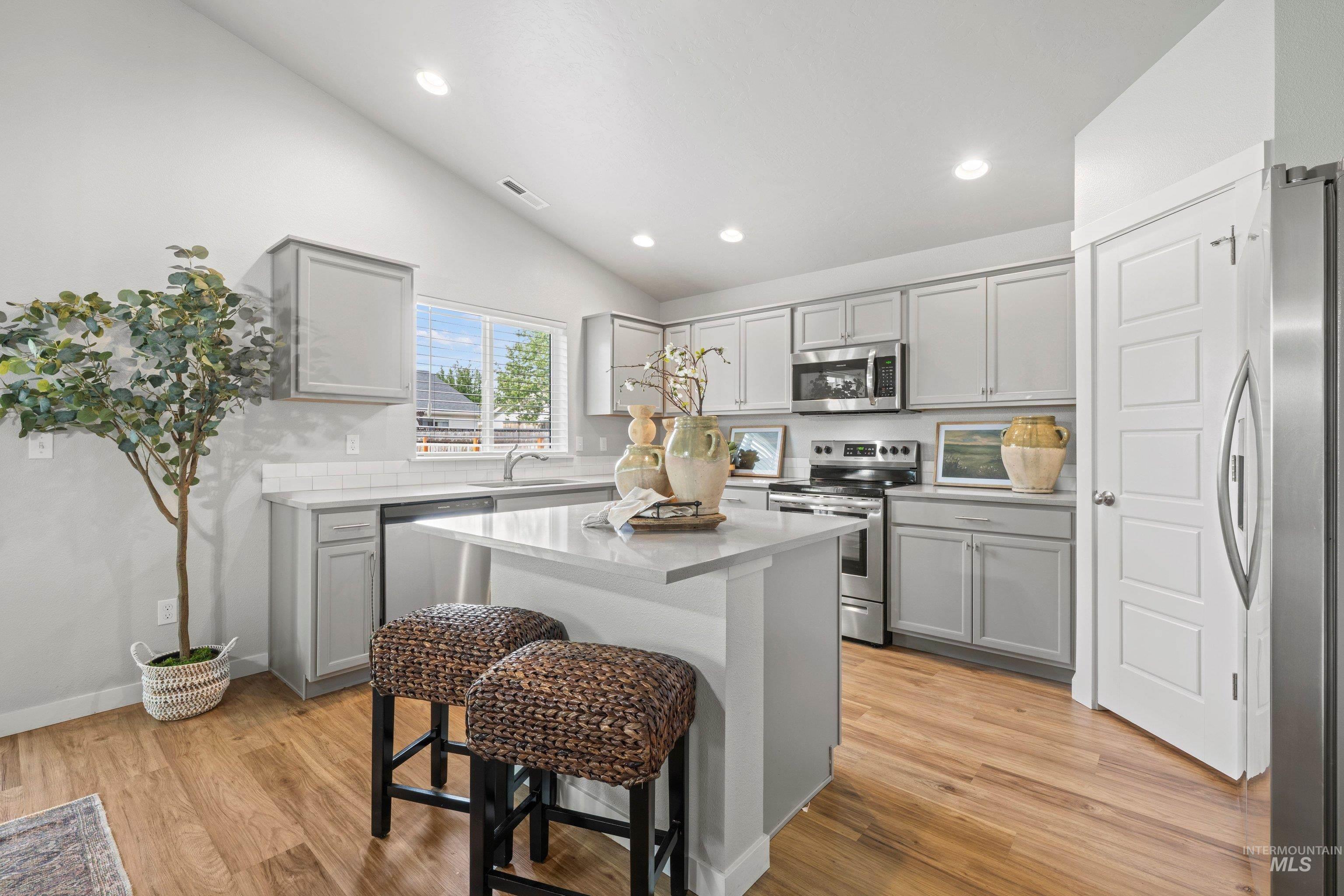 12744 West Fig Street Boise, ID 83713 - Photo 14 of 34 Bright kitchen featuring a central island, recessed lighting, wood-finish flooring, light gray cabinetry, and stainless steel appliances
