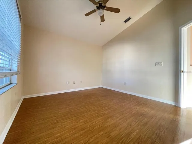 an empty room with a ceiling fan and window