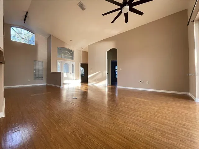 a view of an empty room with window and wooden floor