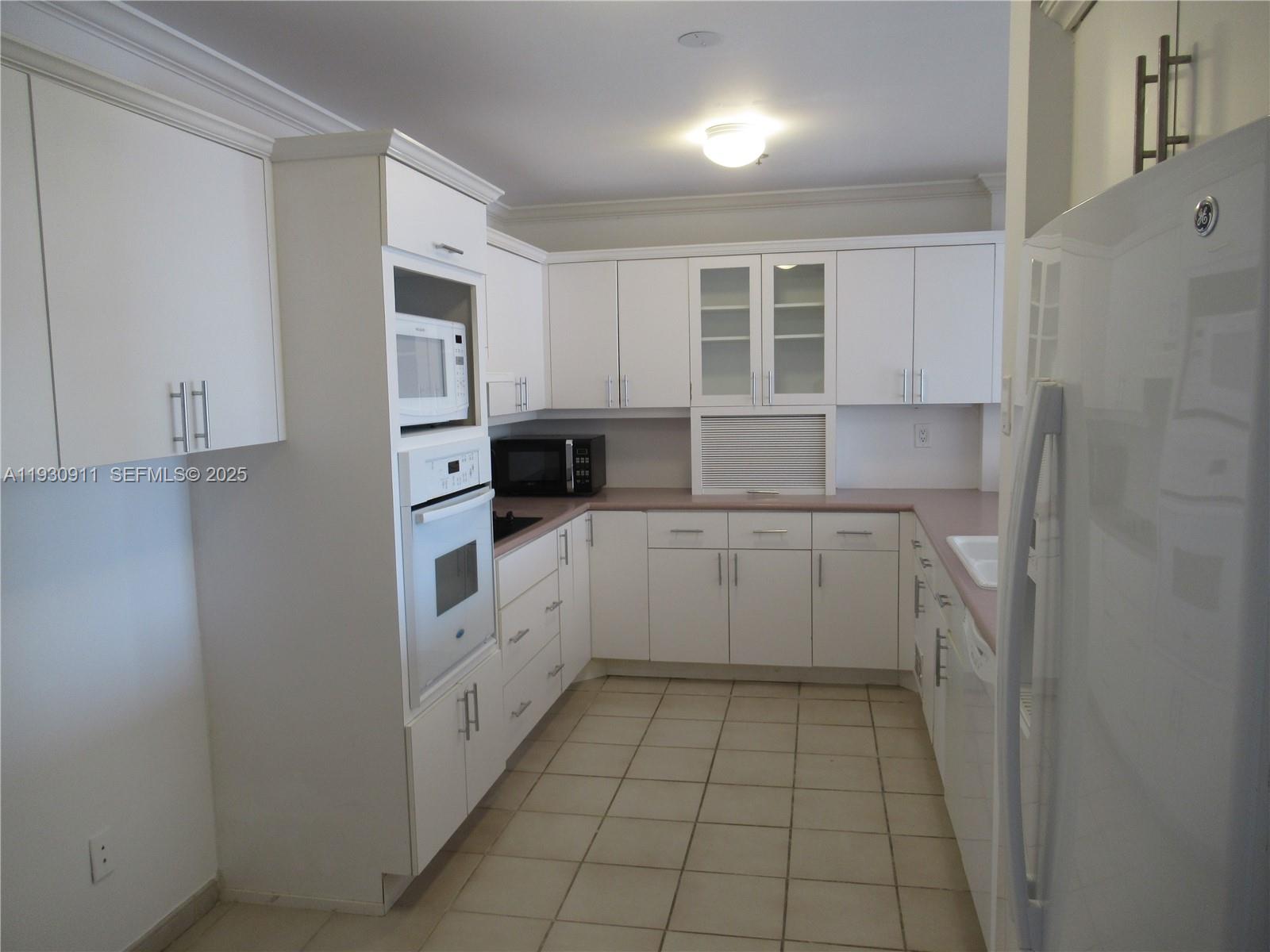 201 Crandon Boulevard, Unit 341 Key Biscayne, FL 33149 - Photo 6 of 25 a kitchen with white cabinets and white appliances