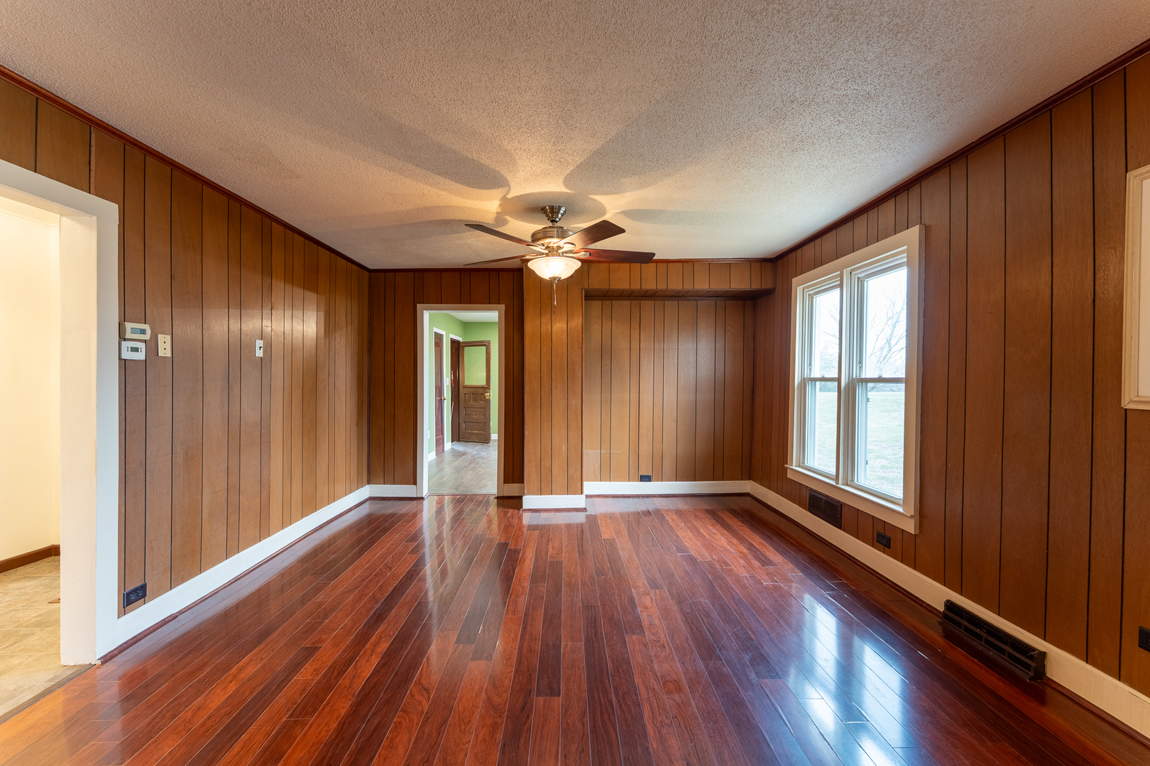 107 Seminary Street Creal Springs, IL 62922 - Photo 19 of 43 a view of an empty room with a window and wooden floor