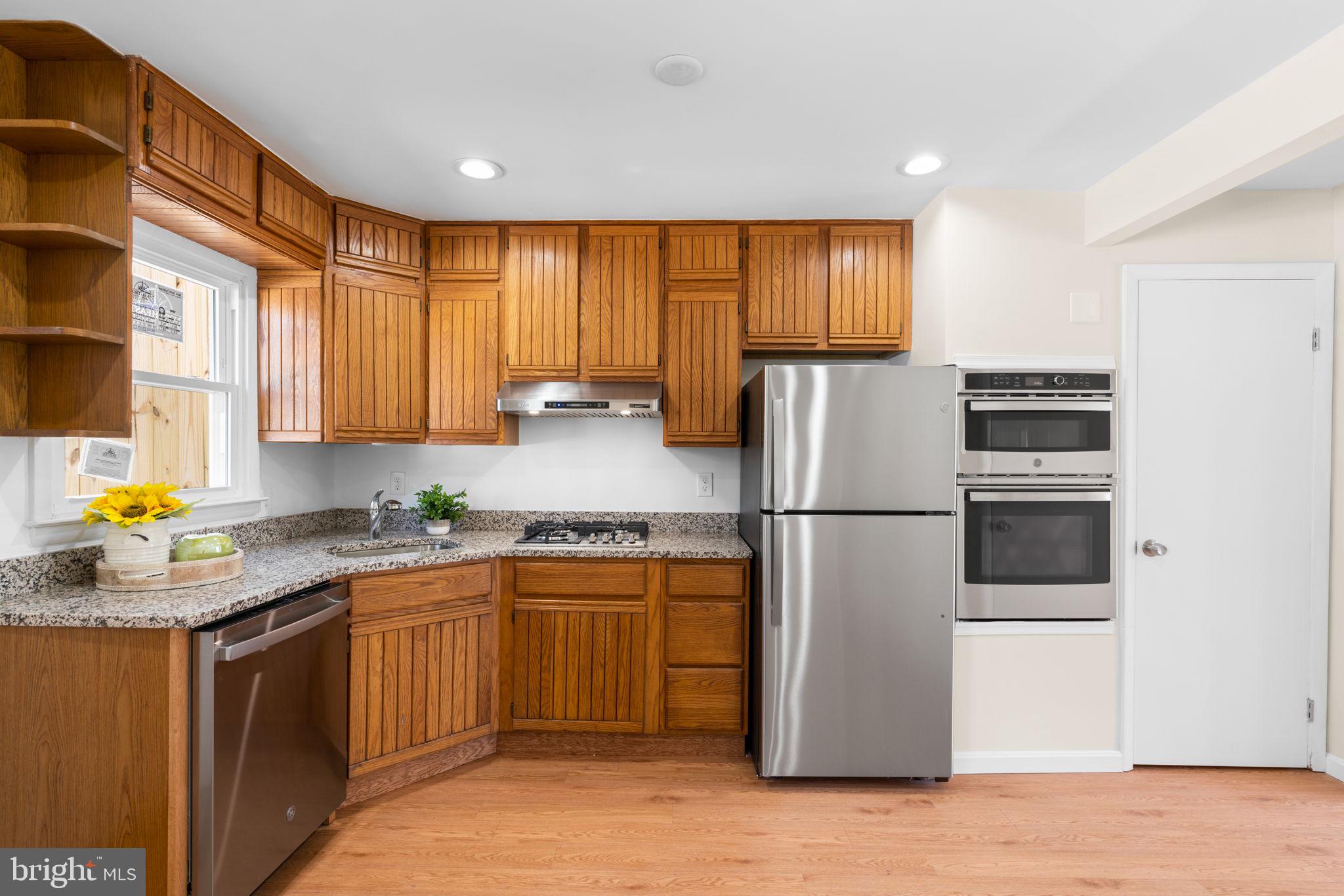 7134 Bexhill Road Windsor Mill, MD 21244 - Photo 11 of 34 a kitchen with a refrigerator a stove a sink dishwasher and wooden cabinets with wooden floor