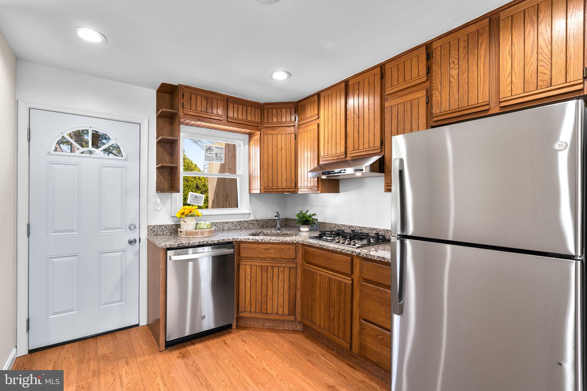 7134 Bexhill Road Windsor Mill, MD 21244 - Photo 10 of 34 a kitchen with stainless steel appliances granite countertop a refrigerator a sink dishwasher a stove with wooden floor and cabinets