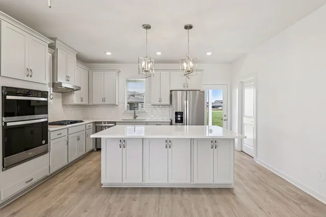 a large kitchen with stainless steel appliances granite countertop a stove top oven a refrigerator a sink and dishwasher