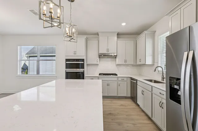 a open kitchen with stainless steel appliances granite countertop a sink a stove a refrigerator and island with wooden floor