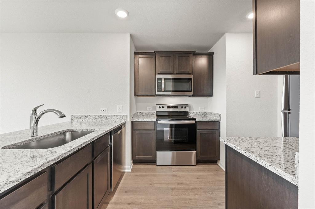 9964 Voyager Lane Fort Worth, TX 76131 - Photo 2 of 10 a kitchen with stainless steel appliances granite countertop a sink stove and refrigerator
