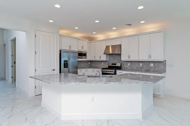 a kitchen with stainless steel appliances granite countertop a stove a refrigerator and a sink