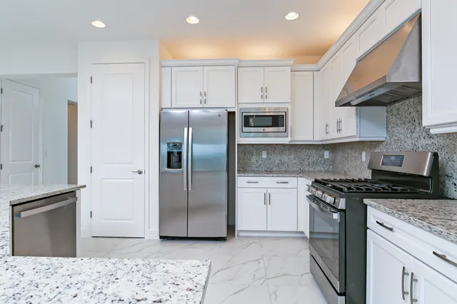 a kitchen with stainless steel appliances granite countertop a stove a sink and a refrigerator