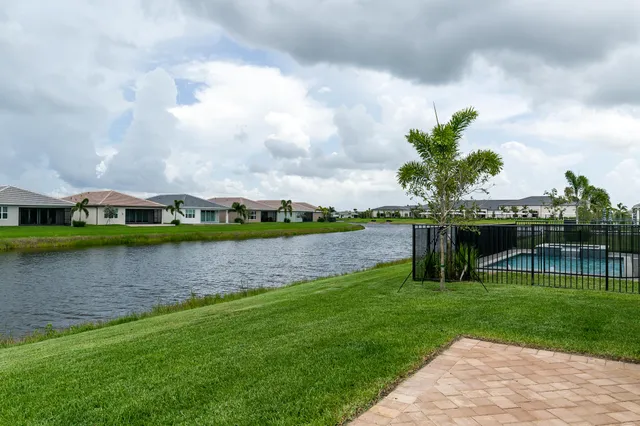 a front view of a house with a garden and lake view