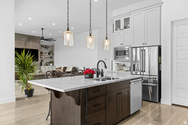 3022 West Sesia Way St. George, UT 84770 - Photo 51 of 52 Kitchen featuring a breakfast bar area, glass insert cabinets, stainless steel appliances, light stone counters, and hanging light fixtures