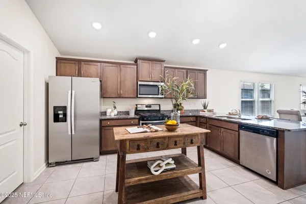 a kitchen with stainless steel appliances granite countertop a stove a sink dishwasher a refrigerator and a microwave