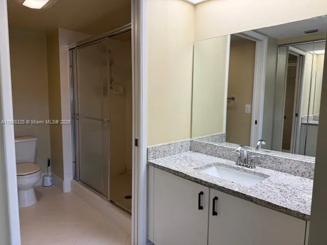 a bathroom with a granite countertop sink a toilet and shower