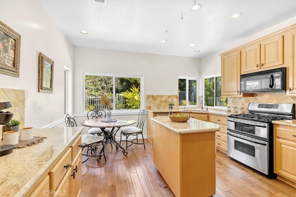 11 Finca San Clemente, CA 92672 - Photo 9 of 55 a kitchen with stainless steel appliances granite countertop a stove top oven a sink dishwasher a dining table and chairs with wooden floor