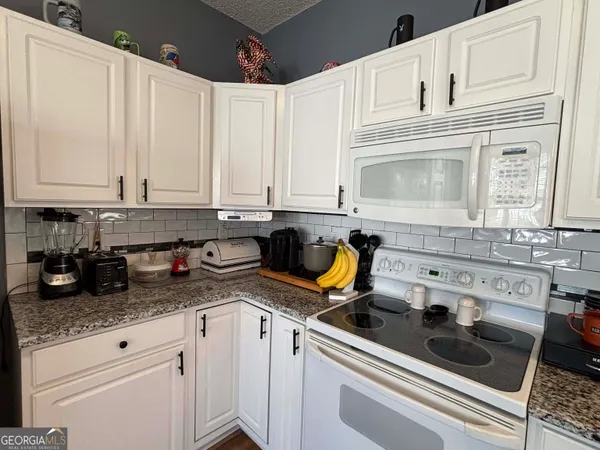 a kitchen with stainless steel appliances a stove top oven a sink a refrigerator and white cabinets