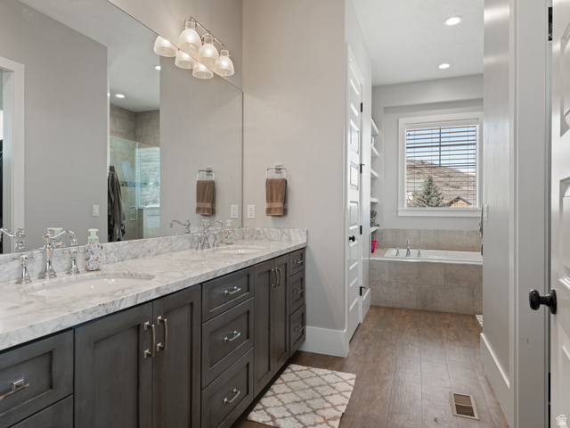 641 West 500 South Midway, UT 84049 - Photo 24 of 52 Bathroom featuring a double vanity with stone countertops and undermount sinks, wood-finish flooring, built-in shelving, and a tiled soaking tub