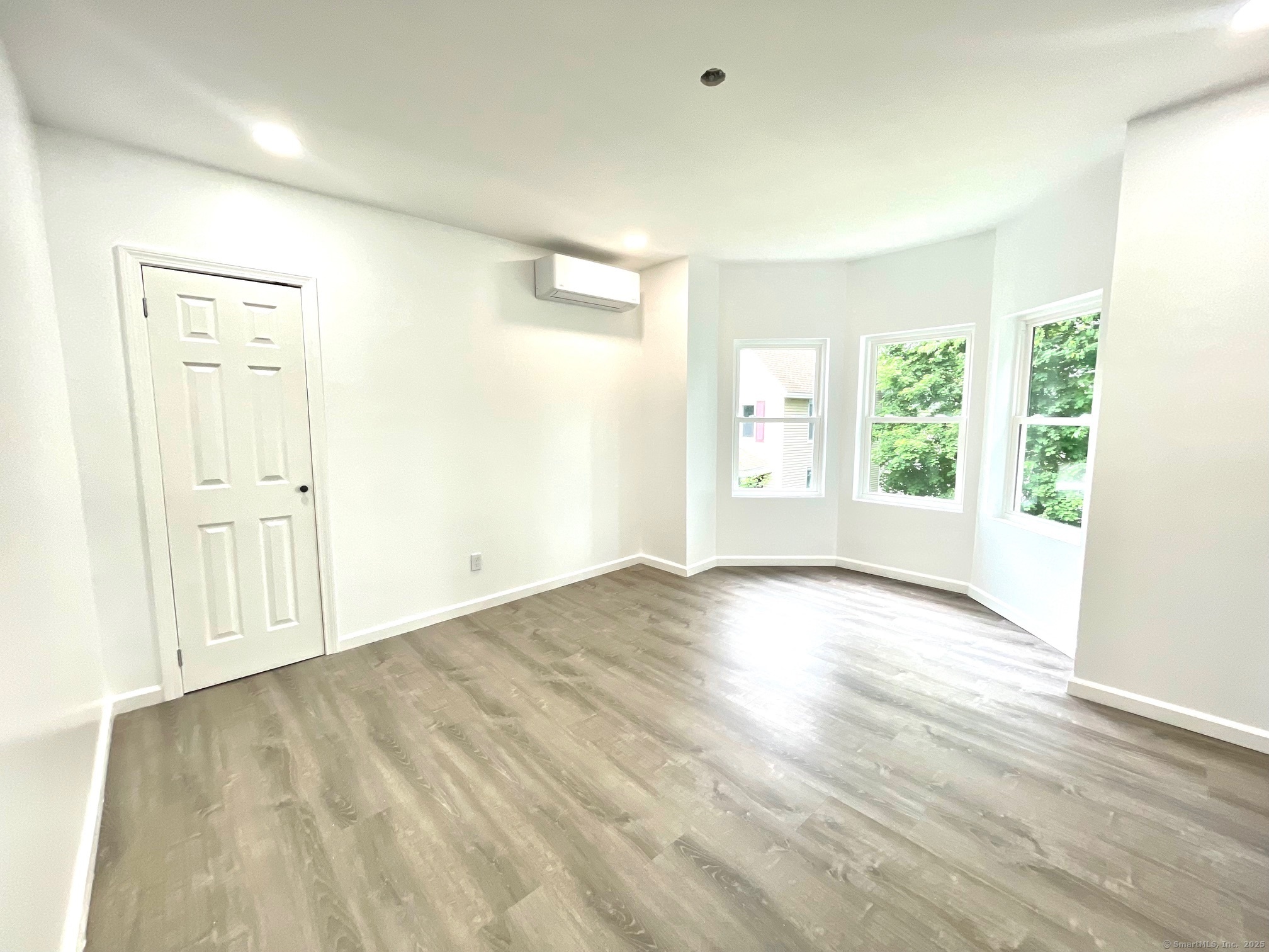 32 Lester Street, Unit 2 Ansonia, CT 06401 - Photo 4 of 9 an empty room with wooden floor and windows