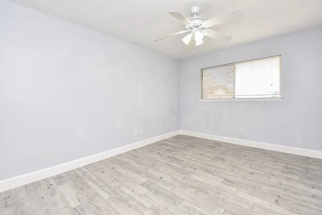 an empty room with a window and a fan