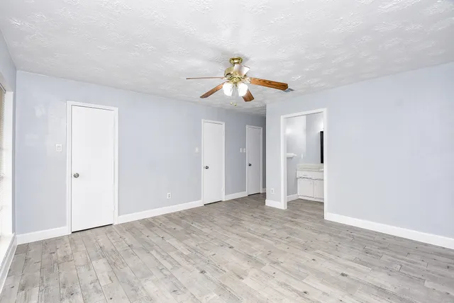 a view of empty room with wooden floor and ceiling fan
