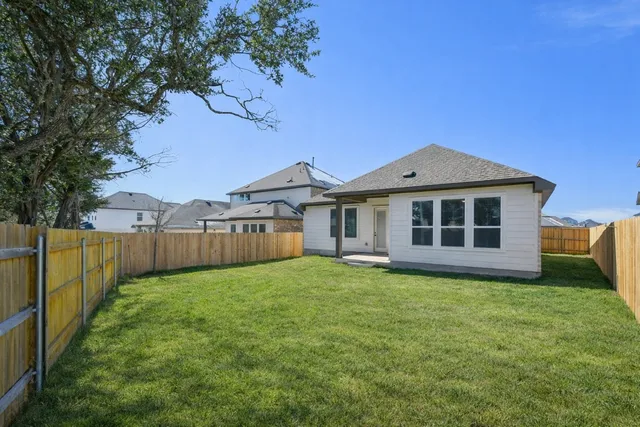 a view of a house with a yard and a large tree