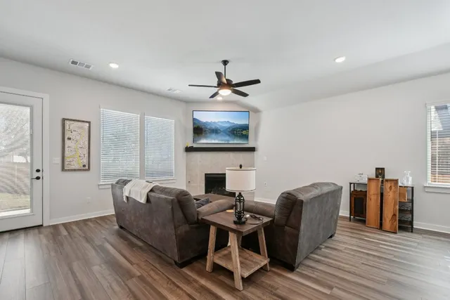 a living room with furniture a fireplace and a ceiling fan