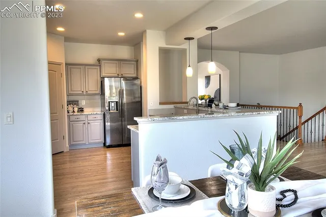 a kitchen with stainless steel appliances kitchen island granite countertop a refrigerator a stove a sink and white cabinets