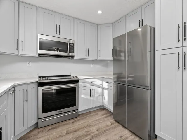 a kitchen with stainless steel appliances white cabinets white stove a microwave and a refrigerator