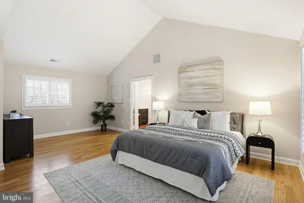 a spacious bedroom with a bed and wooden floor