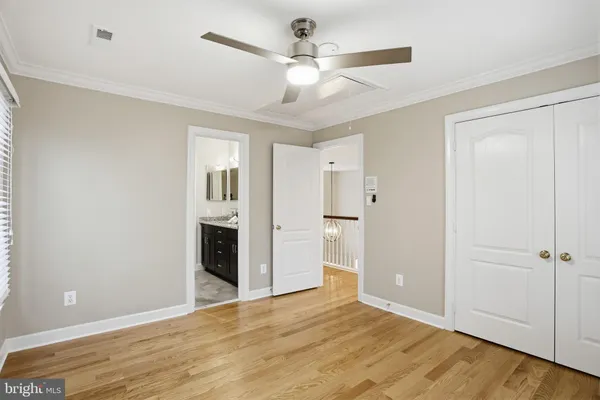 a view of an empty room with wooden floor and a ceiling fan