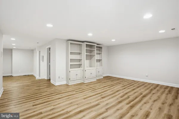a view of an empty room with wooden floor and closet