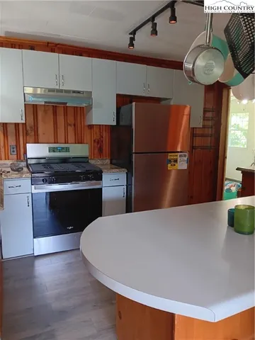 a kitchen with stainless steel appliances granite countertop a refrigerator a stove and a wooden floors