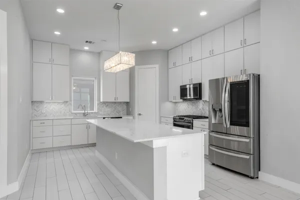 a kitchen with stainless steel appliances kitchen island granite countertop a stove a sink and a refrigerator