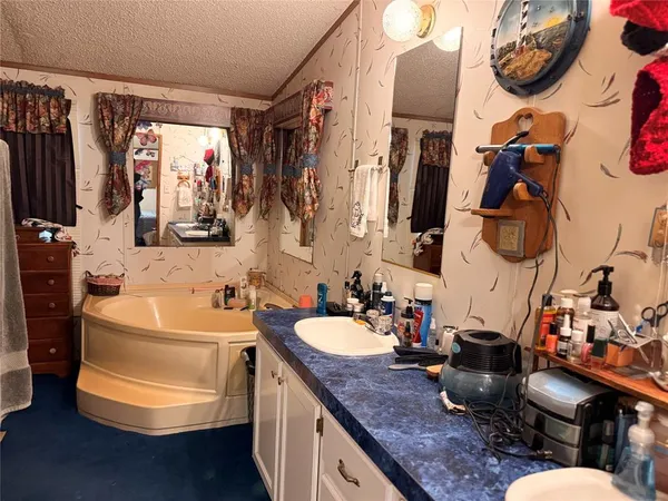 a bathroom with a granite countertop sink a mirror and tub