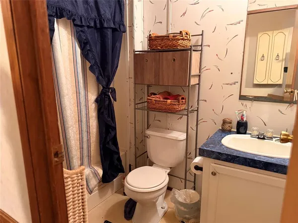 a bathroom with a granite countertop toilet sink and mirror