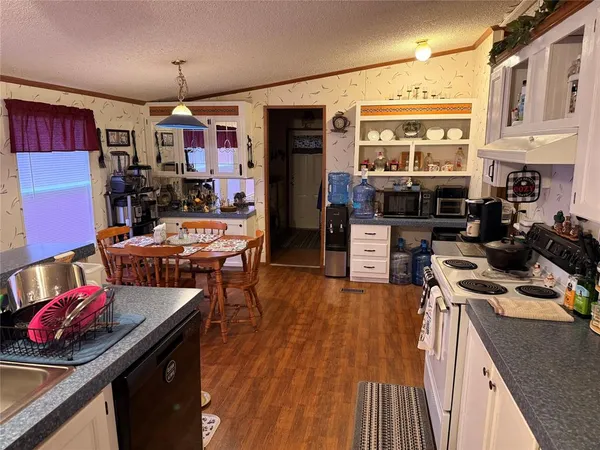 a kitchen with stainless steel appliances granite countertop a stove top oven a sink dishwasher and a dining table with wooden floor