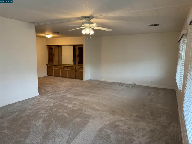 a view of an empty room with a chandelier fan