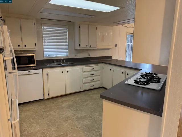 a kitchen with granite countertop a sink stove and cabinets