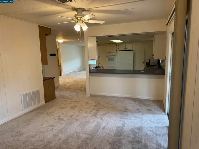 en empty room with a mirror and a ceiling fan