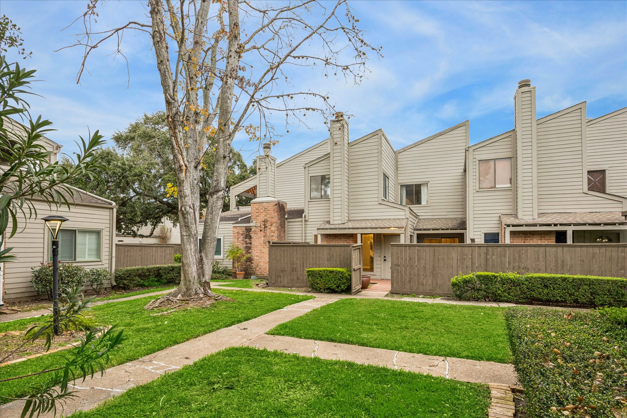 1615 Prairie Mark Lane Houston, TX 77077 - Photo 2 of 25 From the huge courtyard, you enter through the open gate that you see. There is guest parking adjacent to the courtyard from the townhome. The roof, fence and exterior are taken care of by the HOA. Gutters were just installed in 2025.