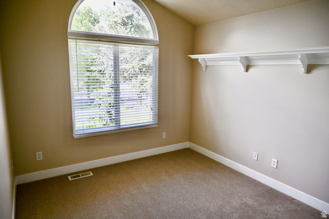 314 Brown Farm Lane Draper, UT 84020 - Photo 21 of 57 Arch-top window with blinds, featuring tan wall paint, white trim, carpet flooring, and a decorative wall shelf