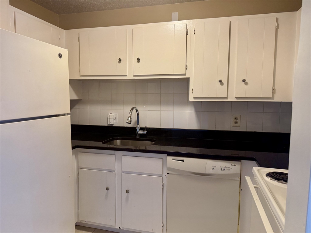 1186 Worcester Road, Unit 720 Framingham, MA 01702 - Photo 11 of 15 a kitchen with granite countertop white cabinets and a sink