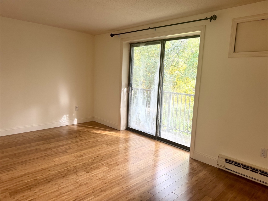 1186 Worcester Road, Unit 720 Framingham, MA 01702 - Photo 8 of 15 a view of an empty room with wooden floor and a window