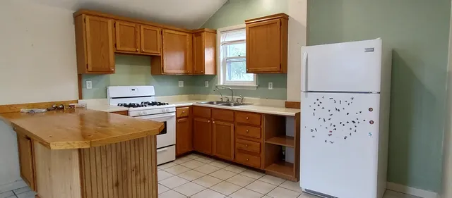 a kitchen with stainless steel appliances a refrigerator a sink and wooden cabinets