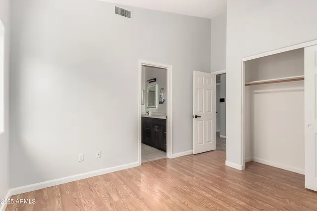 a view of an empty room with wooden floor and closet