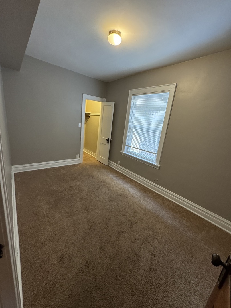 6840 South Champlain Avenue, Unit 2 Chicago, IL 60637 - Photo 8 of 12 an empty room with a window and a kitchen