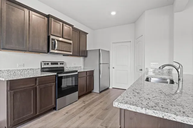a kitchen with stainless steel appliances granite countertop a stove sink microwave and refrigerator