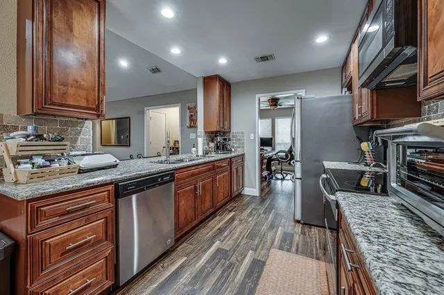 a large kitchen with stainless steel appliances a large counter top a stove and a sink