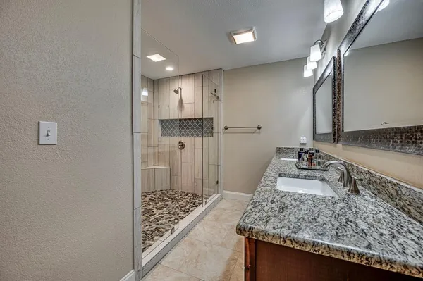 a bathroom with a granite countertop sink a toilet and shower